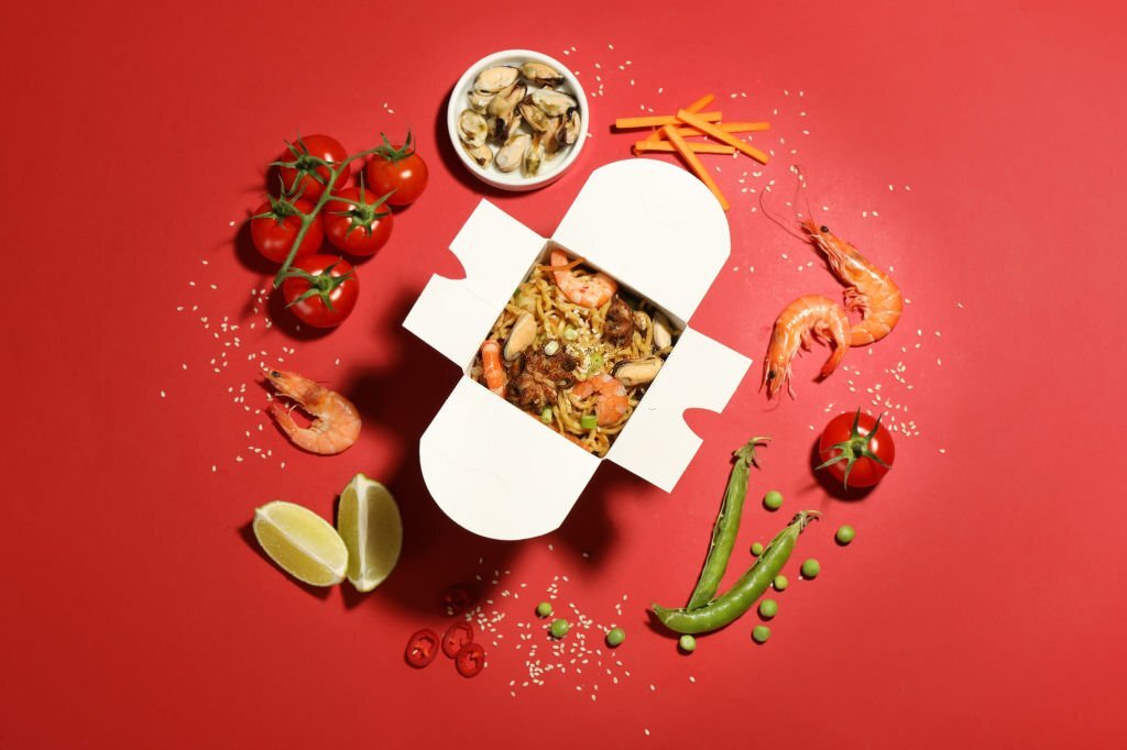 Flat lay composition with noodle wok and ingredients on red background